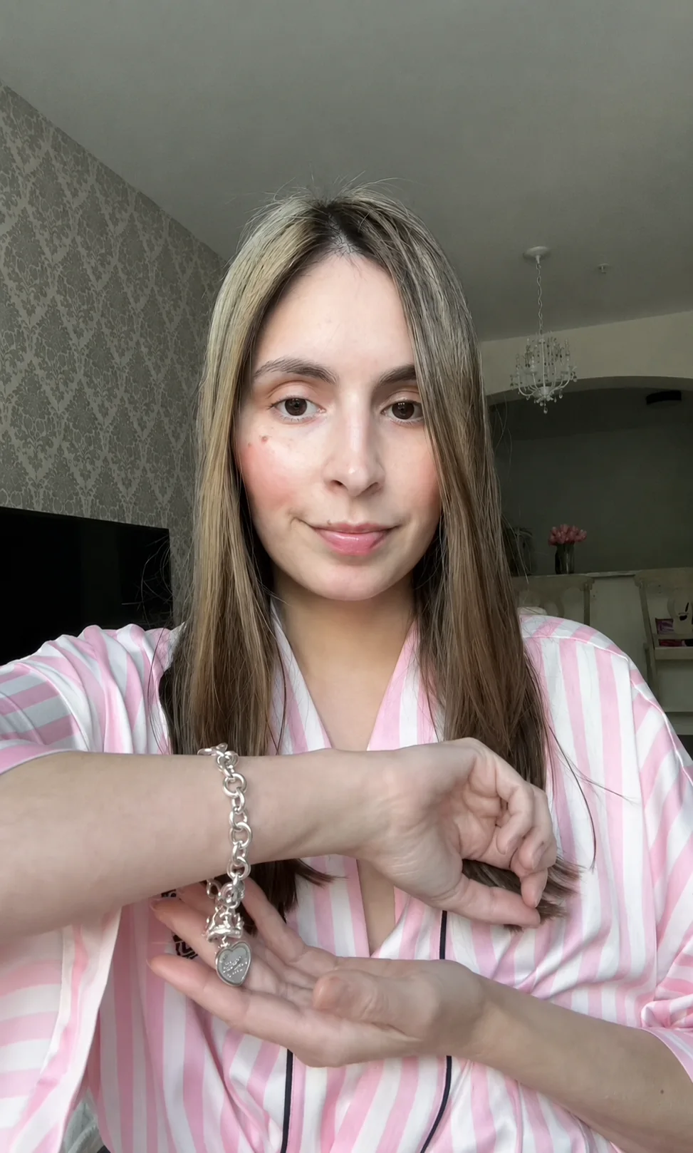 Customer wearing a silver charm bracelet at home